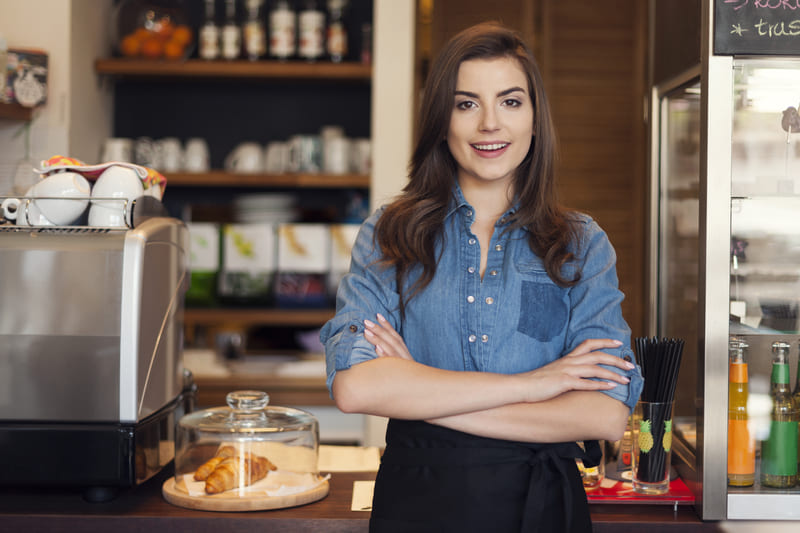 franquias baratas - foto de empreendedora feliz na sua franquia de cafeteria